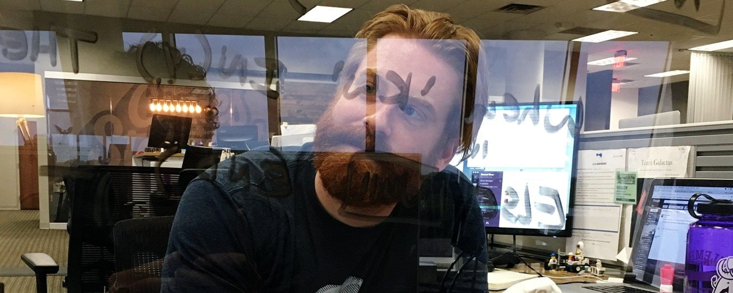 Marketer peeking through transparent marker board with a silly look